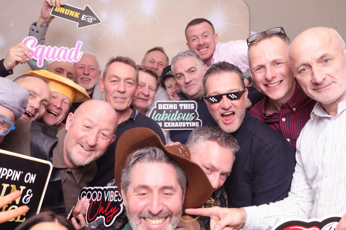 A big group of guests squeezing into the photobooth with props